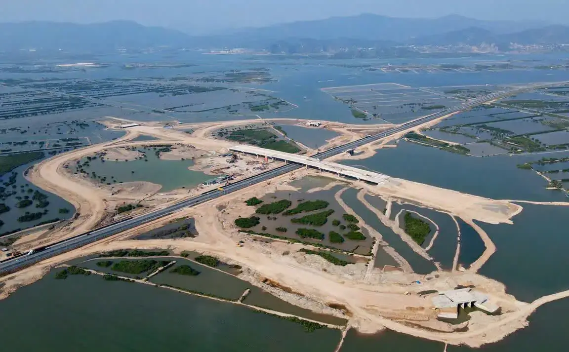 Flycam tiến độ thi công dự án cho thấy hạ tầng giao thông, cầu vượt và hệ thống san lấp mặt bằng đang được triển khai đồng bộ giữa không gian sông nước rộng lớn.
